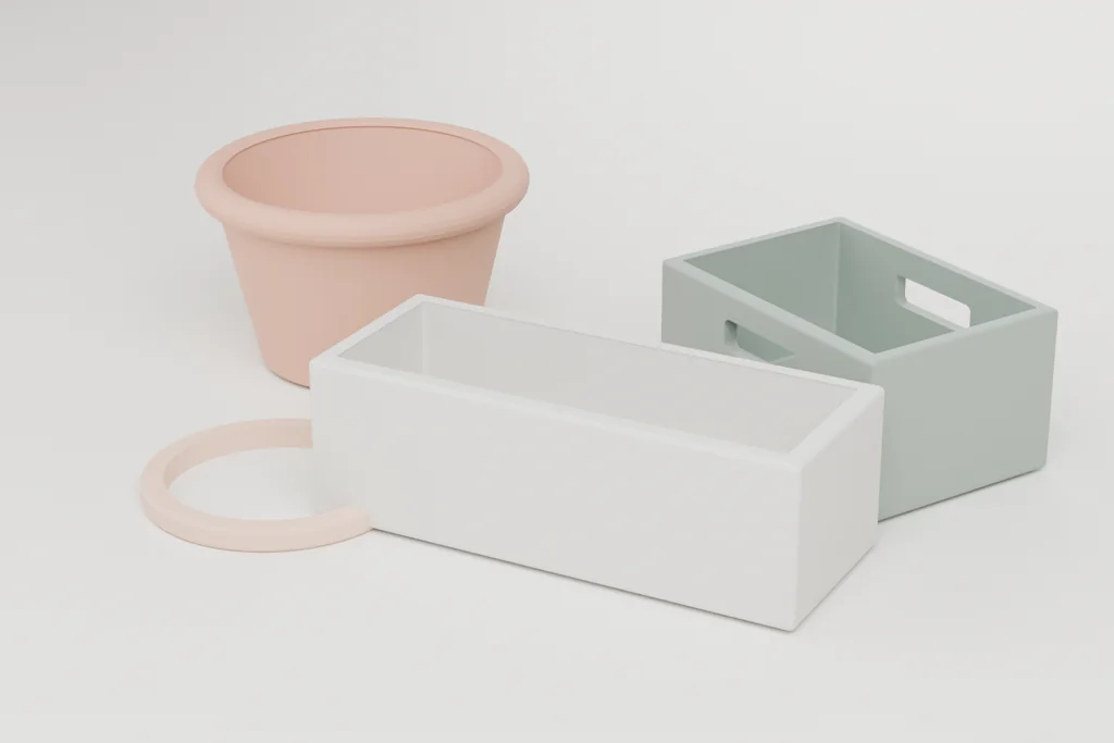 Three garden objects on a pale surface: a terracotta tapered planter, a white stone trough on feet, and a sage stacking crate.