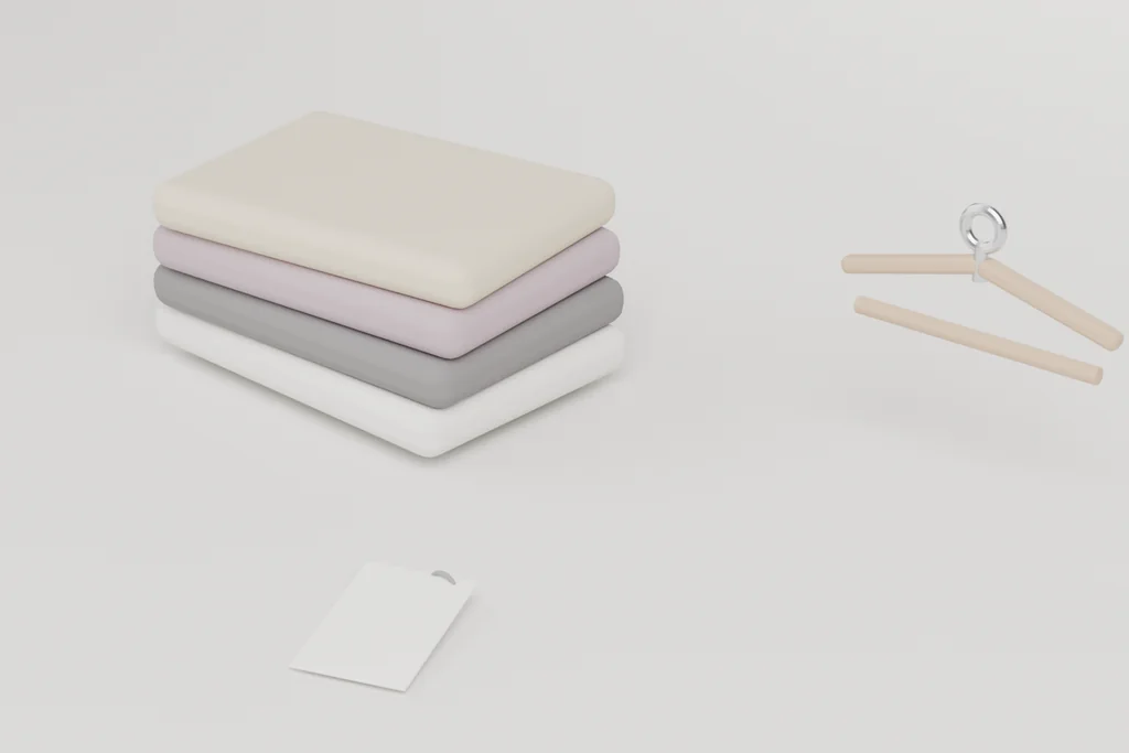 A stack of four folded knits in cream, lilac, grey and white, a wooden hanger with a metal hook, and a woven label with a swing tag.